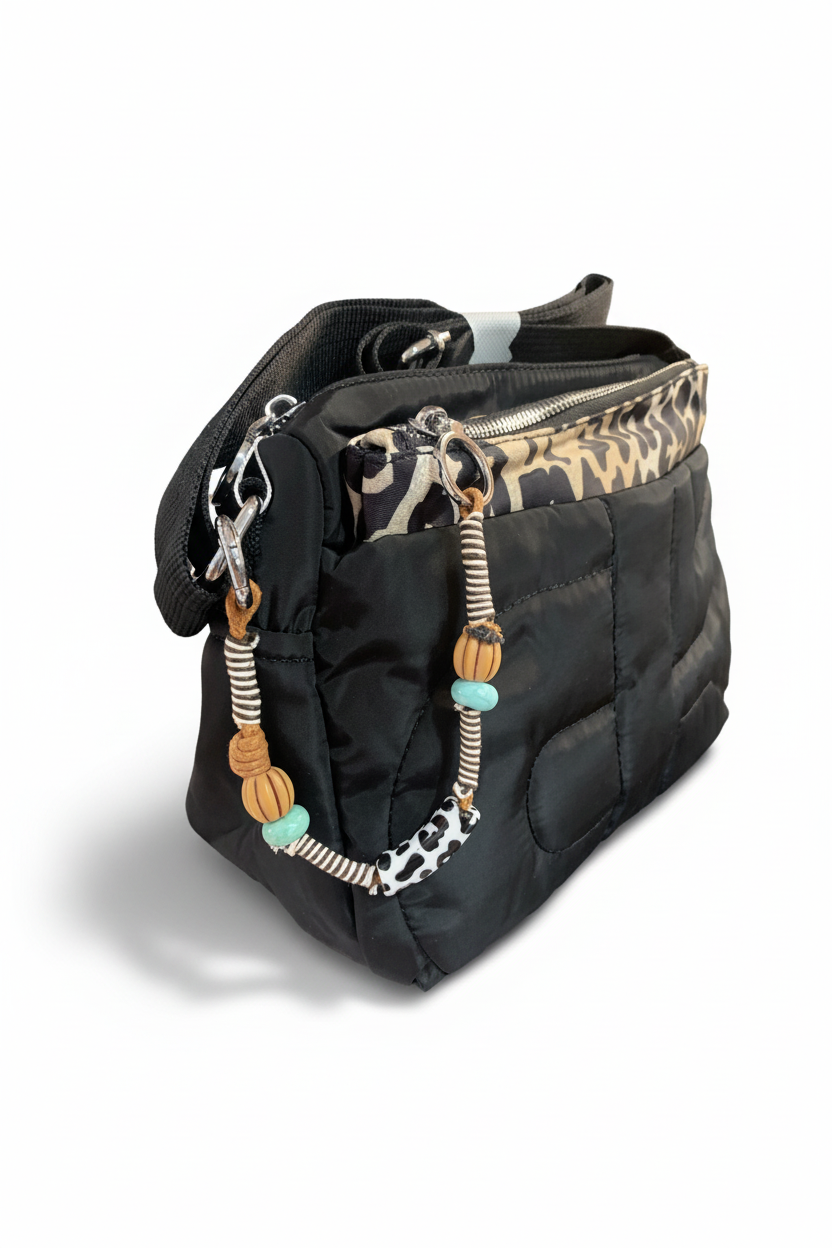Bolso bandolera acolchado negro, vista lateral con colgantes de cuentas