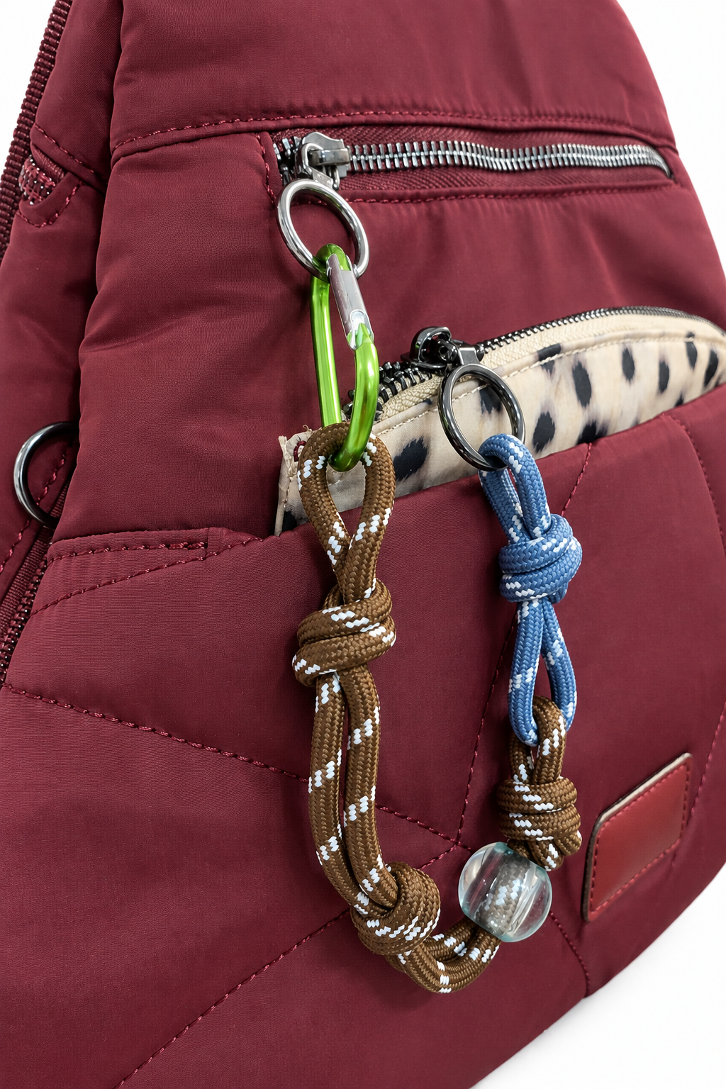 Detalle de mochila burdeos con bolsillo delantero, cremalleras y adornos